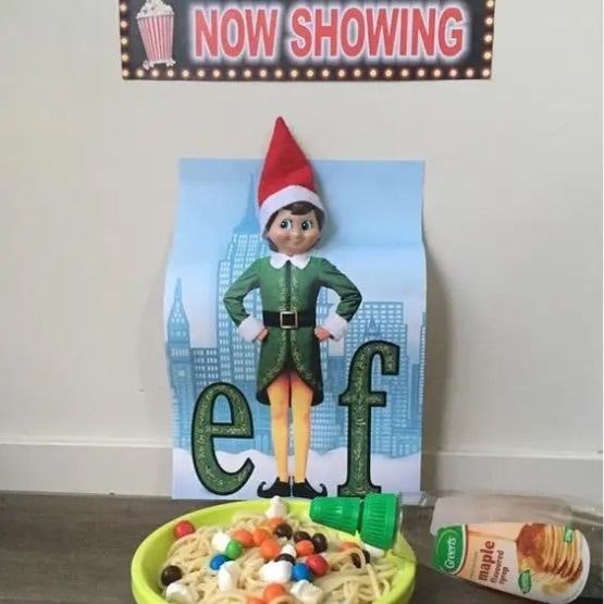 Elf in a Buddy the Elf poster with its head opopping rhought popping through and a plate of spaghetti with sweets and syrup