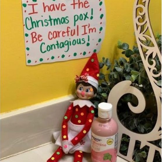 Elf covered in dots next to a bottle of medicine with a sign saying 