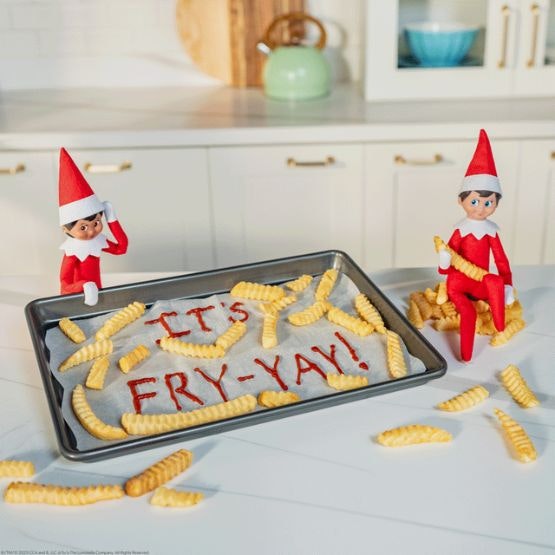 Two elves with a baking tray of fries and a sign in ketchup saying 