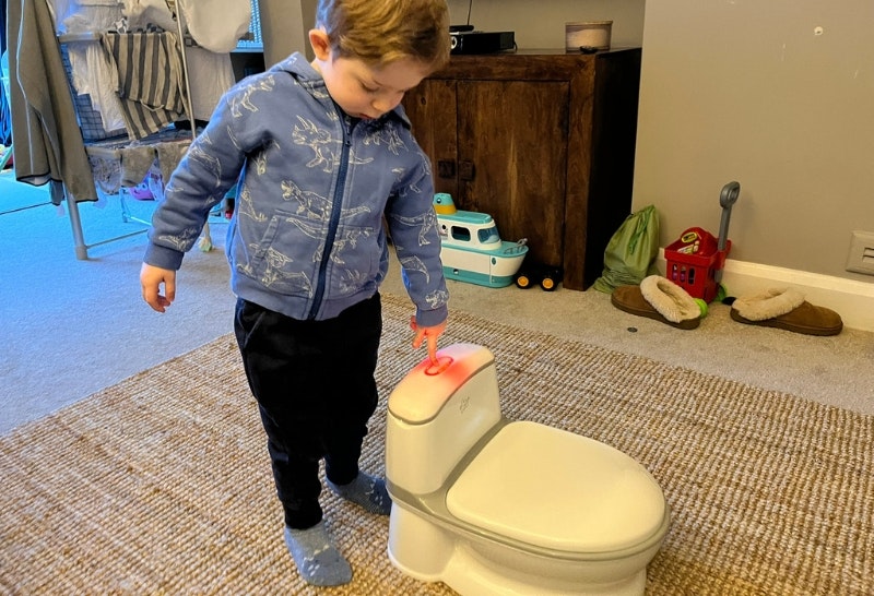 young boy pressing the flush button on the Pote Plus My First WC
