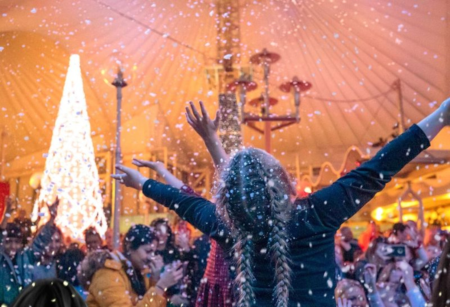 A little girl with her hands in the air enjoying snow at Christmas at Butlins