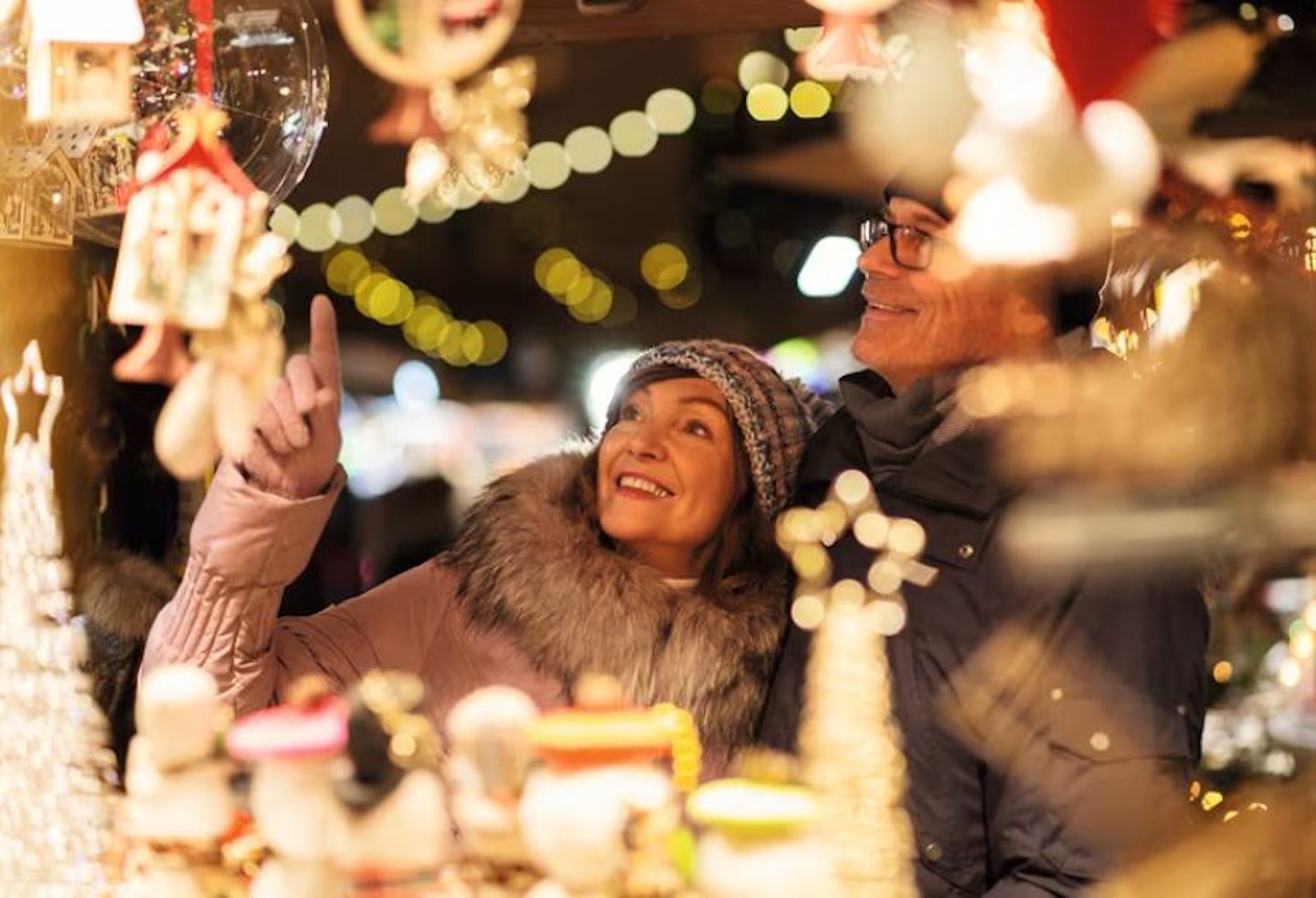 A man and woman looking up at Christmas lights and framed by twinkling lights