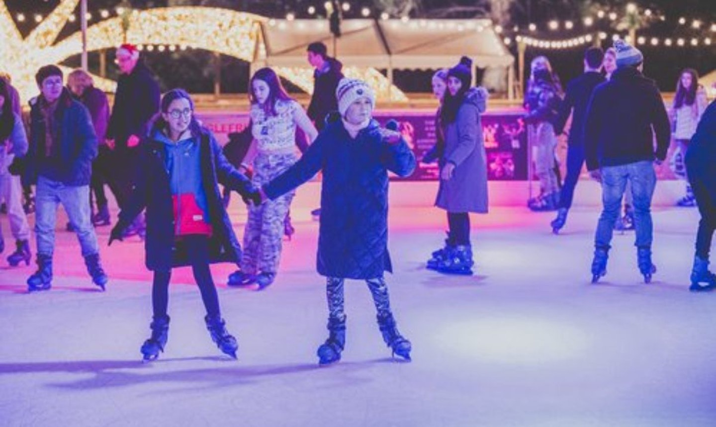 Two chlidren holding hands and skating around Cardiff ice rink