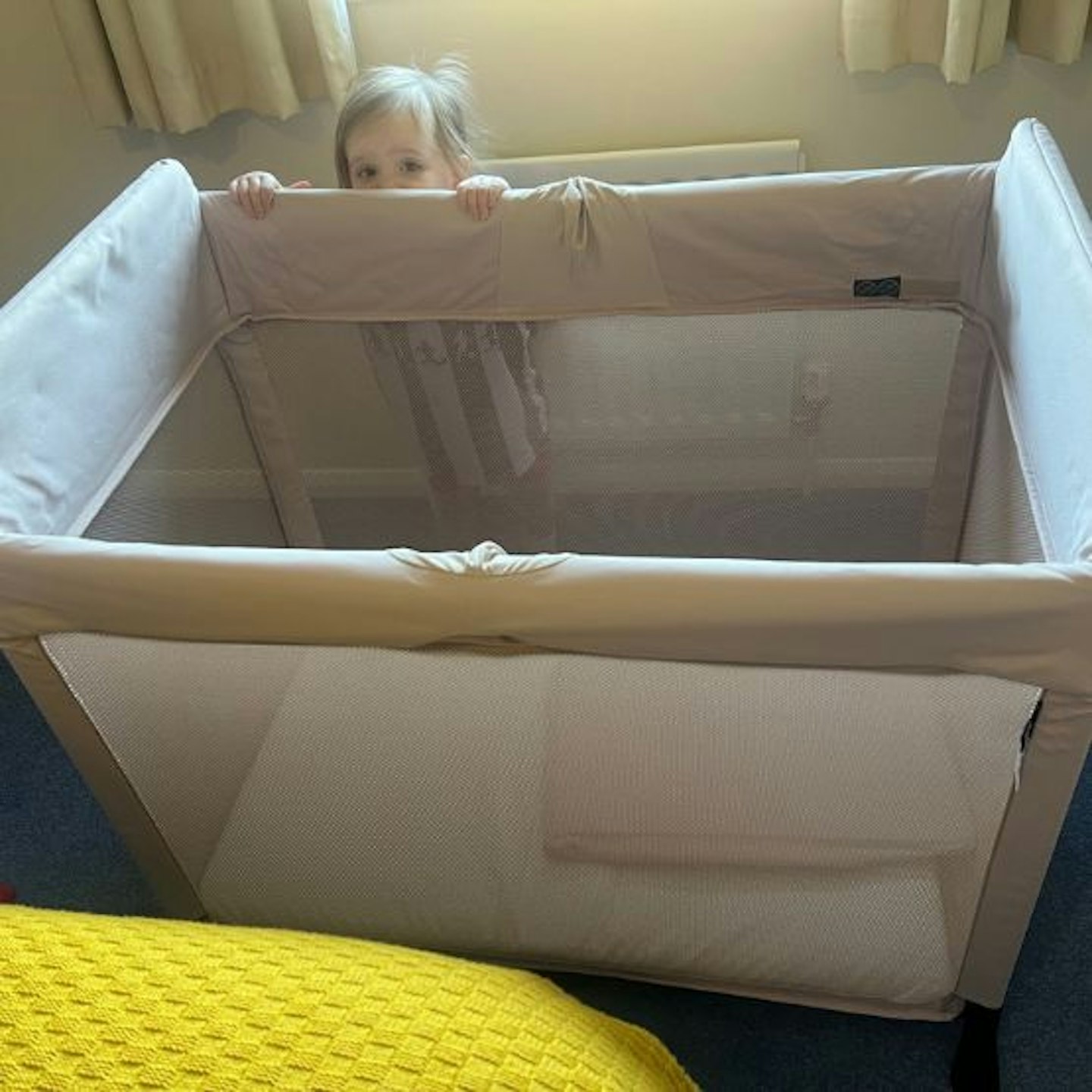 A toddler standing behind the Bugaboo Stardust ready to test the travel cot
