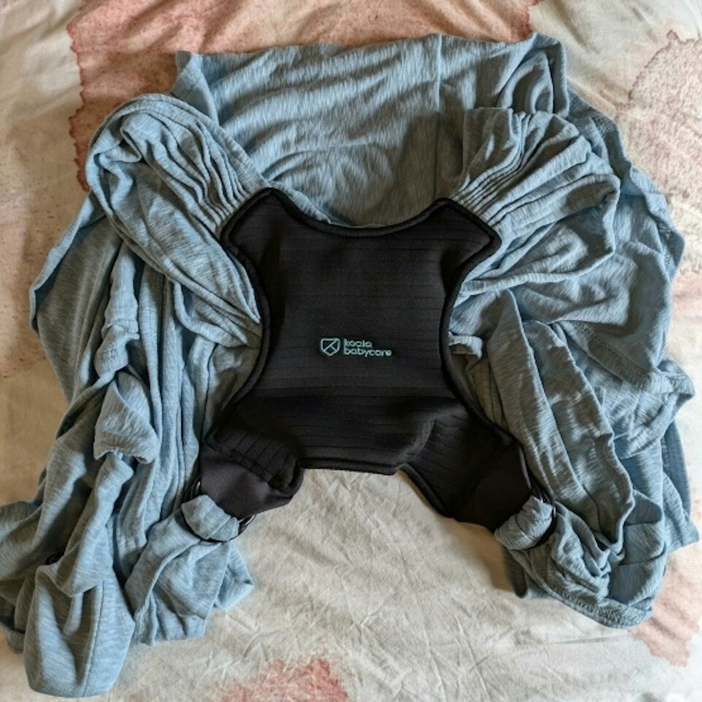 Koala Cuddle Band Baby Sling laid out on a bed
