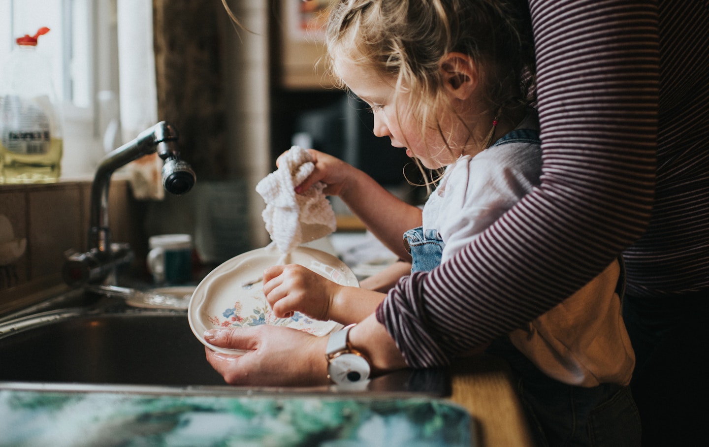 Child doing the washing up to help the family.