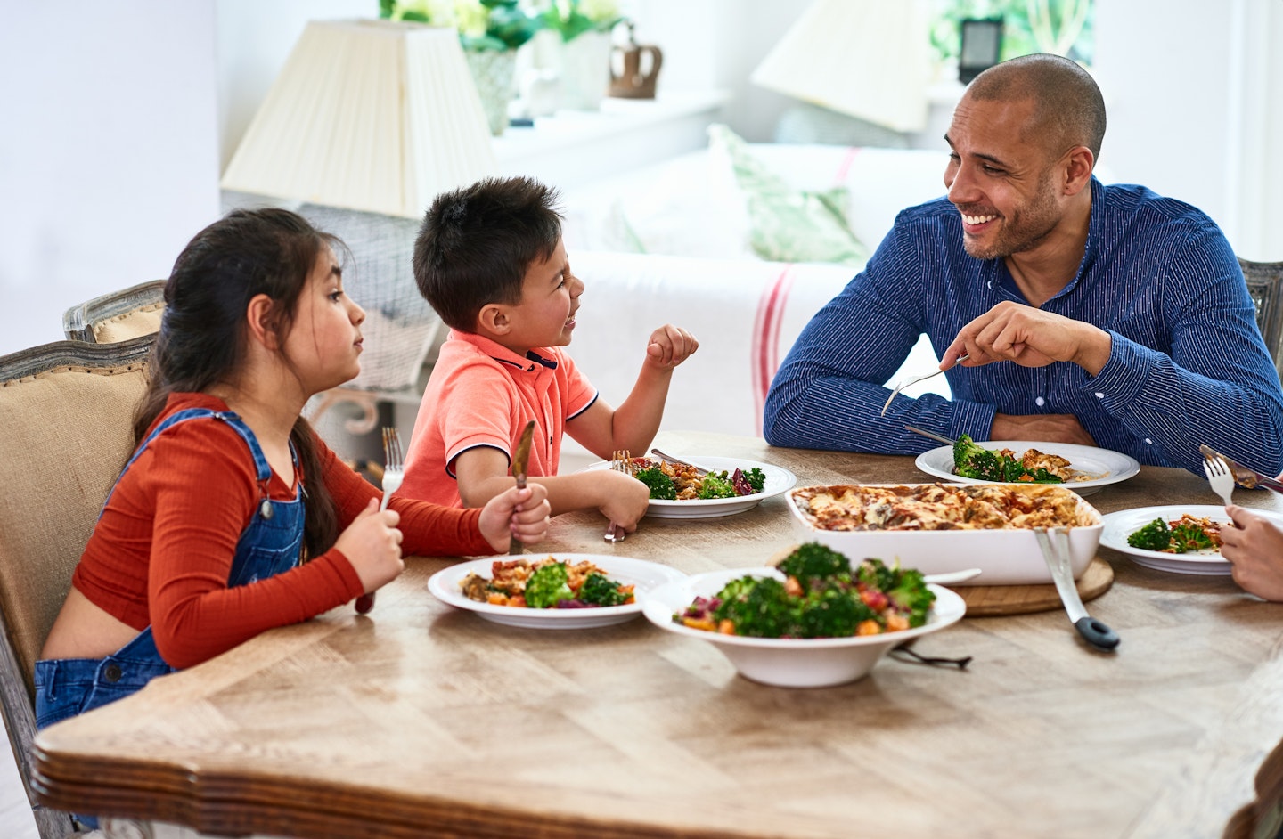 Two children and their father enjoying a meal together.