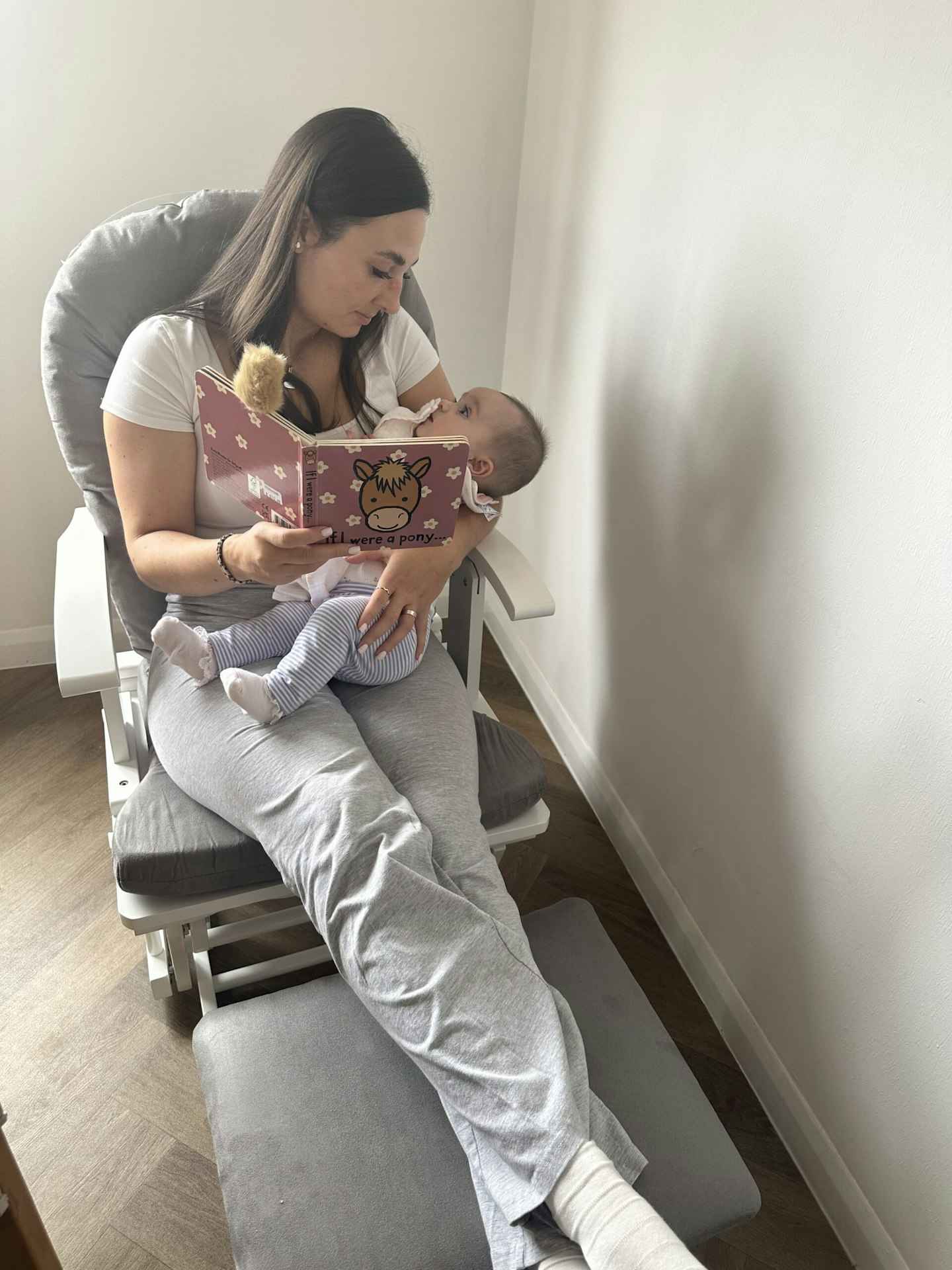 Mum tester Charlotte sitting in Obaby reclining and gliding chair and stool holding baby Margot