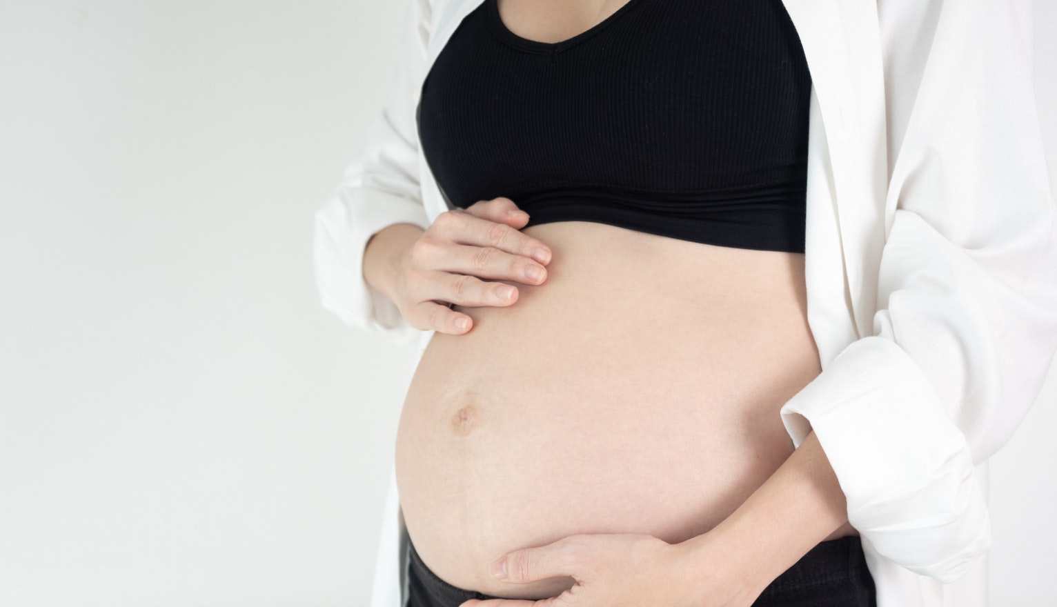A 6 month pregnant woman showing her bump and her outward belly button