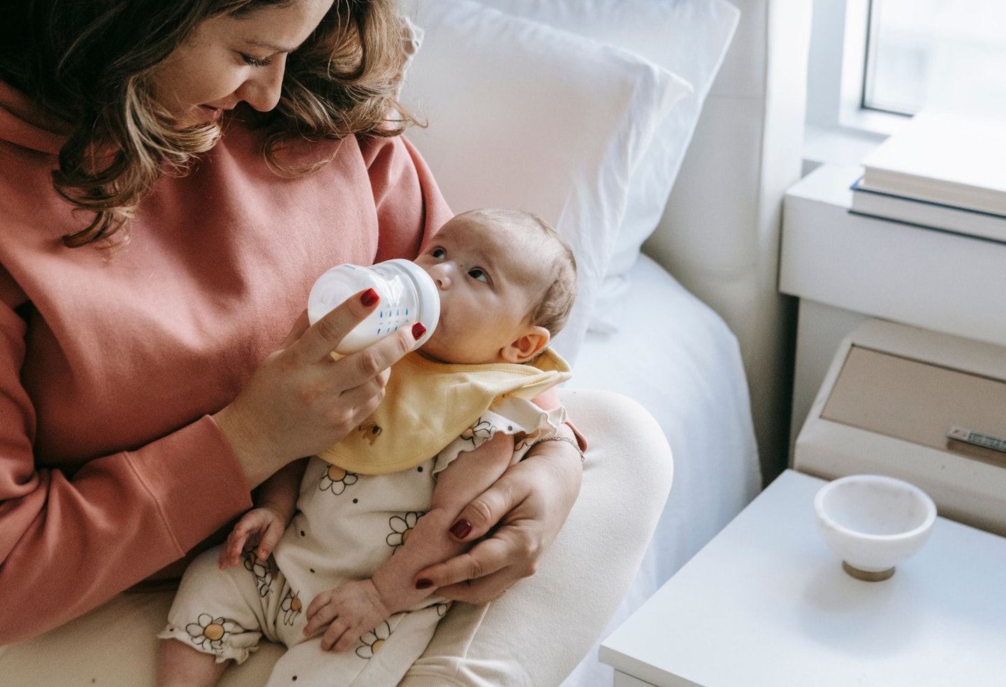 Smiling young mother feeding baby with milk from bottle