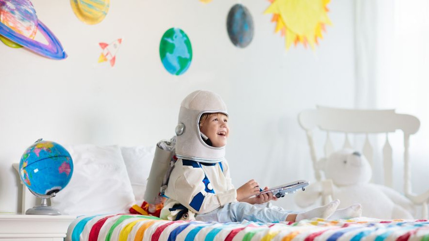 Child sitting in a space themed bedroom