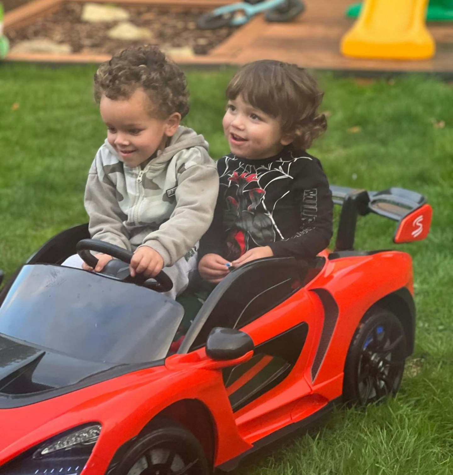 Toy little boys testing the McLaren Licensed 12V Kids Electric Ride-On Car.