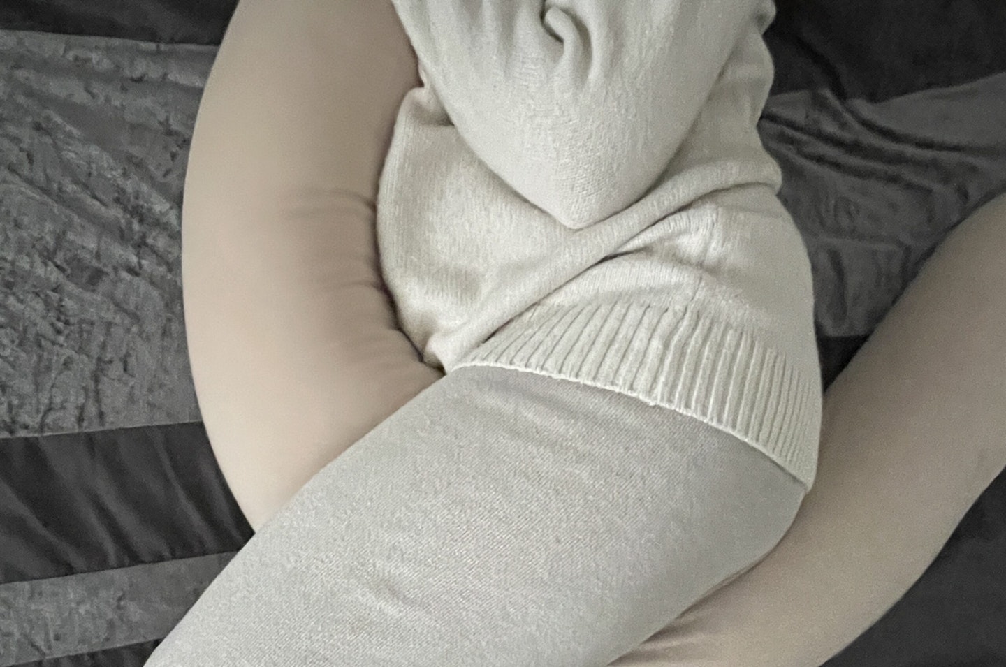 A pregnant woman curled up with the Najell pregnancy pillow 