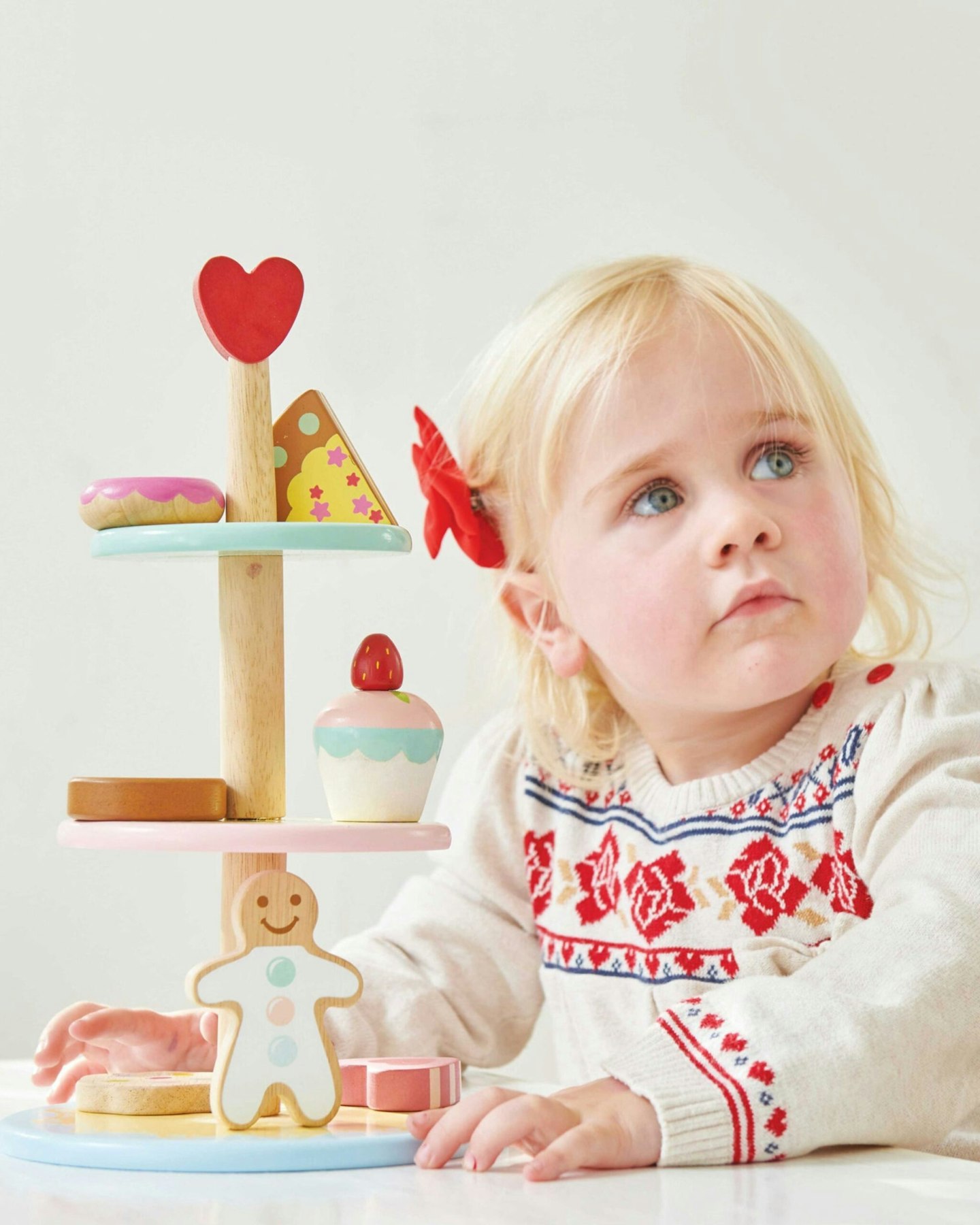 Little girl next to a toy patisserie cake stand