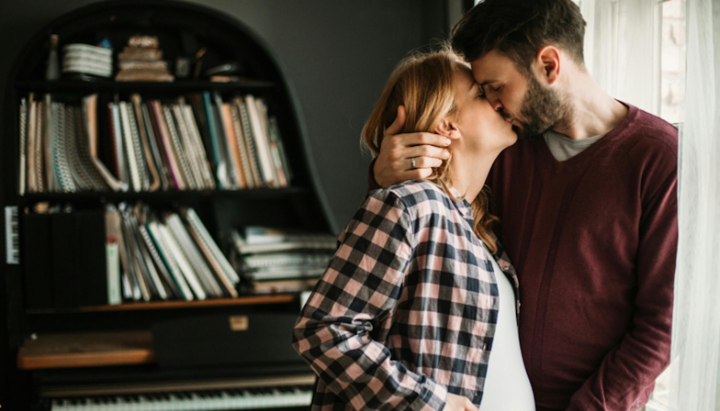 pregnant woman and partner kissing
