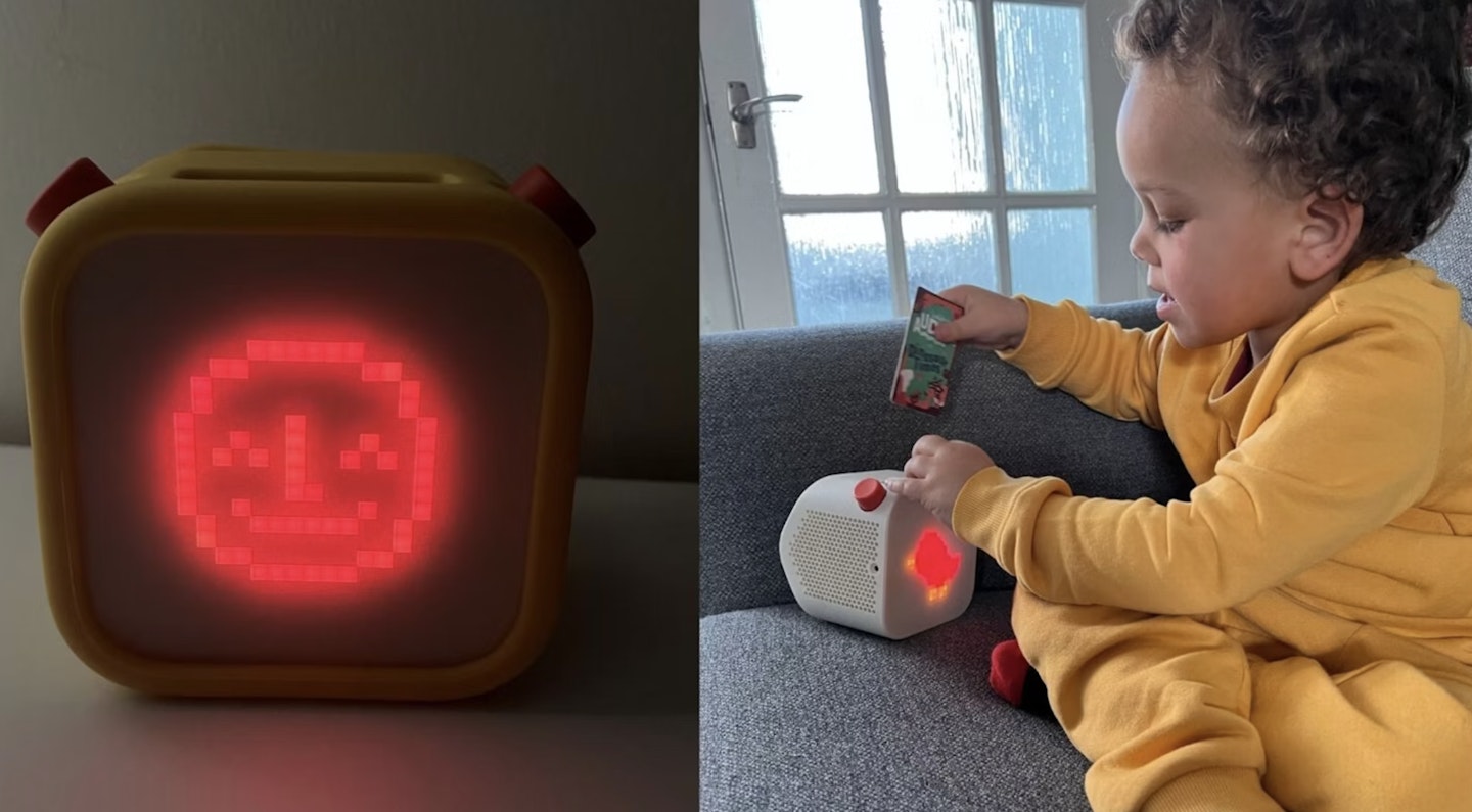 A little boy sitting on the sofa playing with a yoto player