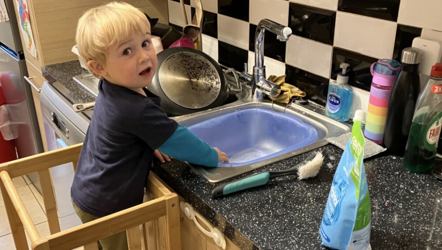 A toddler testing out the  
COSYLAND Kitchen Kids Standing Tower 