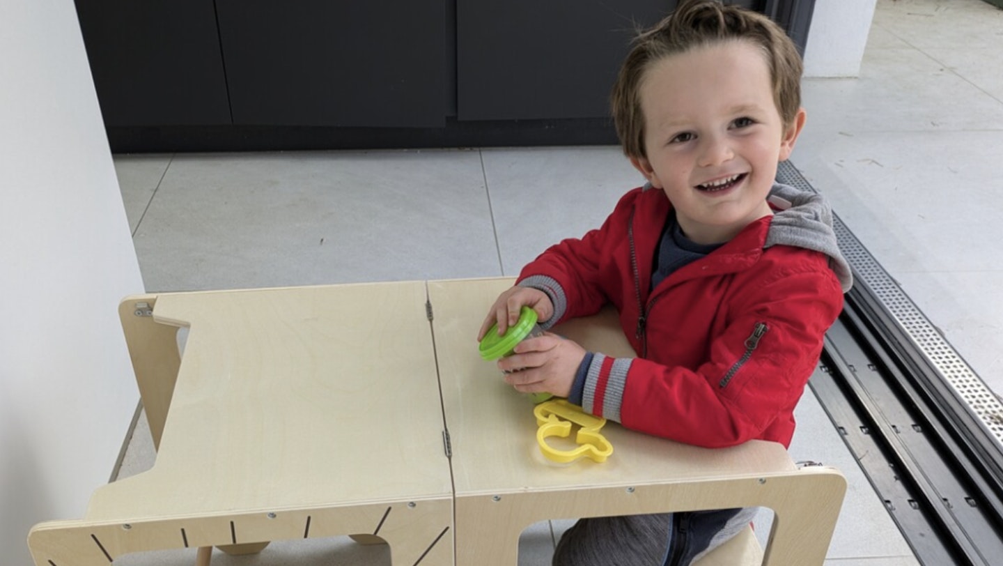 An image showing a toddler testing out the Kids Step Stool, Learning Wooden Tower with Chalkboard kids learning toddler tower that transforms into a table
