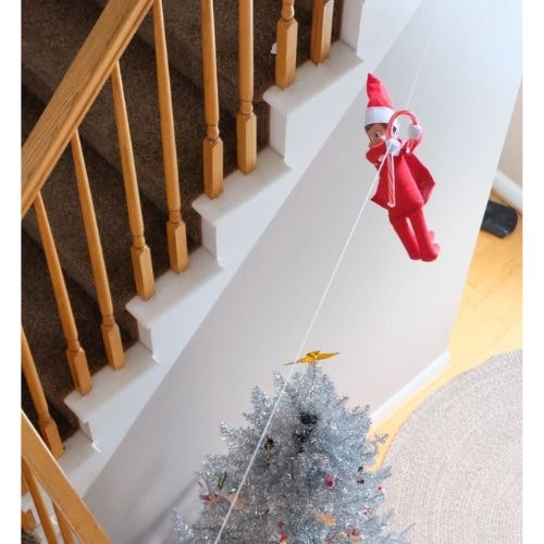 An elf on the shelf ziplining down a staircase