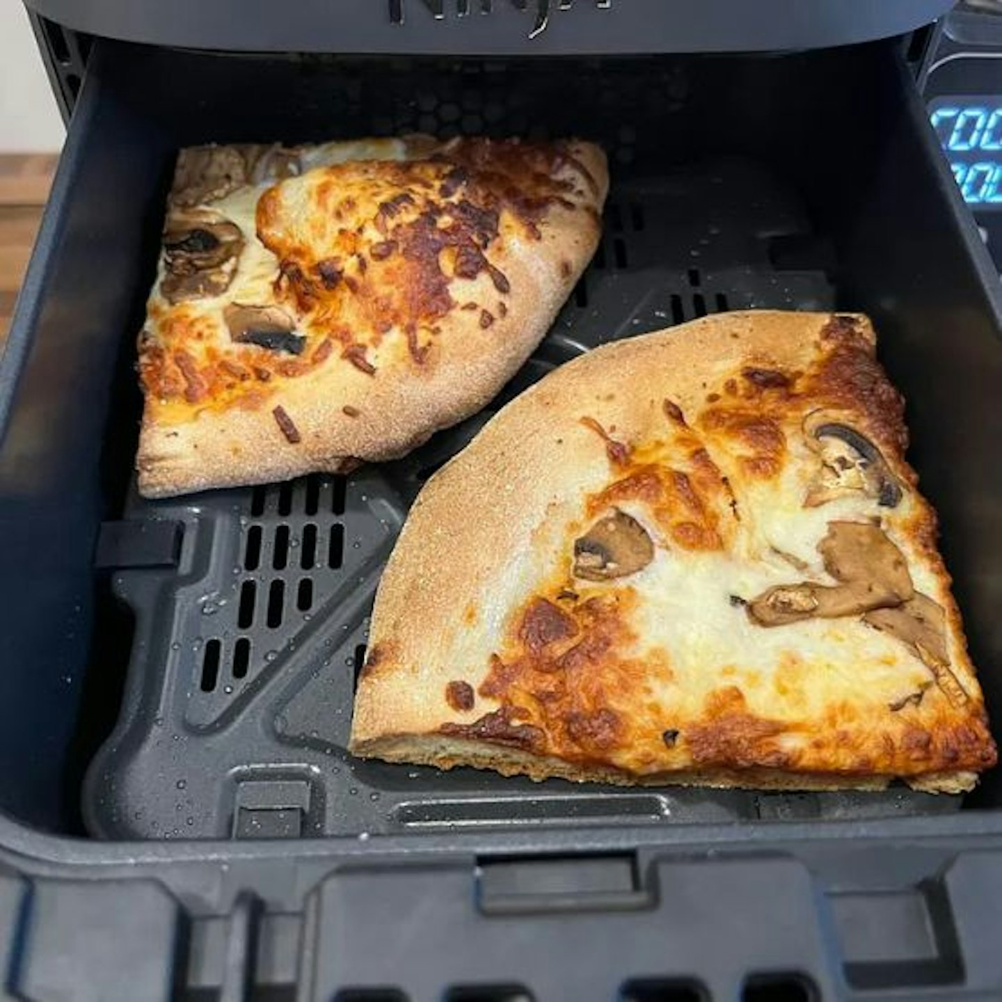 Two slices of pizza cooked in the top rack of the Ninja Double Stack XL Air Fryer