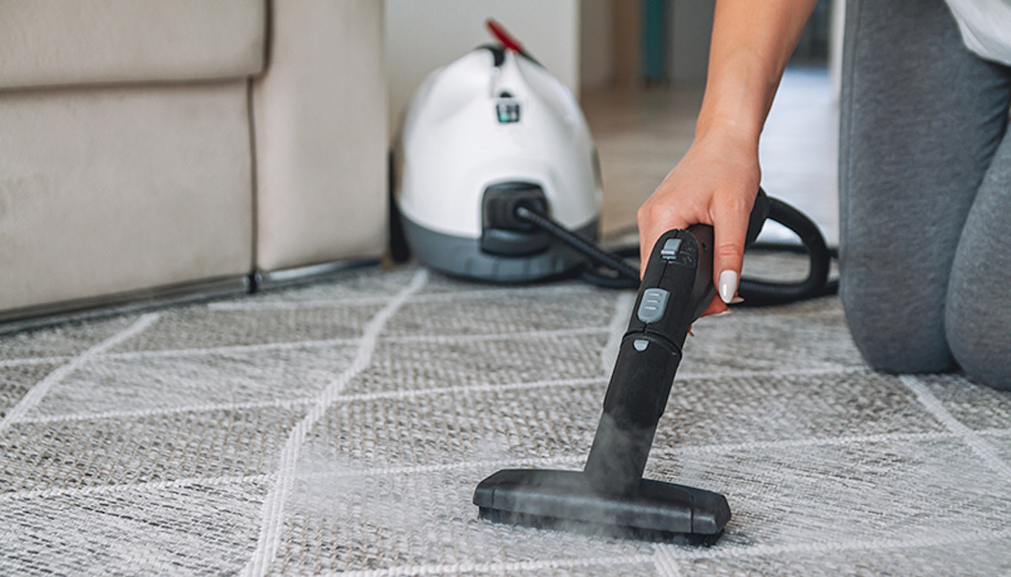 Woman cleaning carpet with a steam cleaner