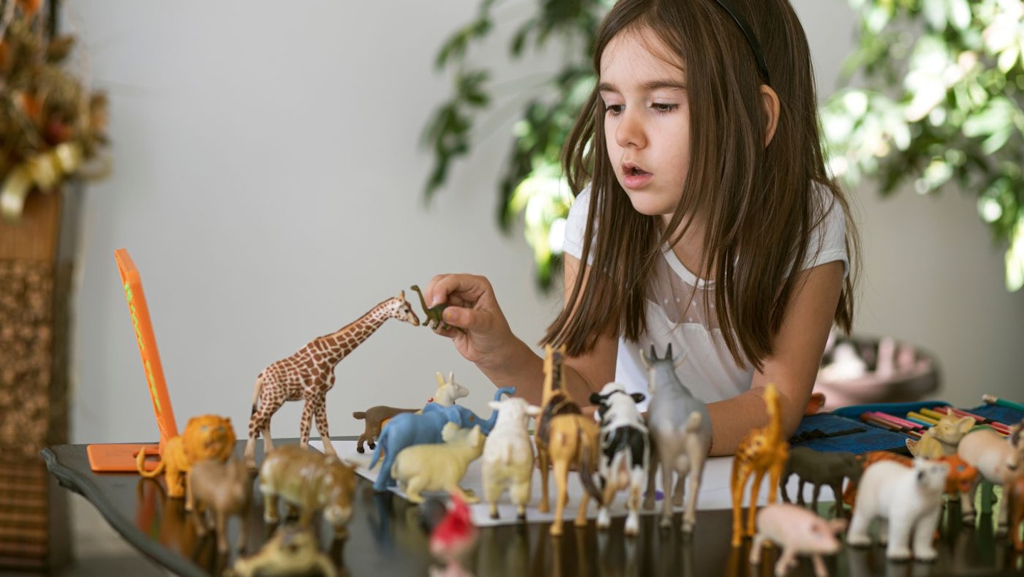 A young girl playing with animal toys