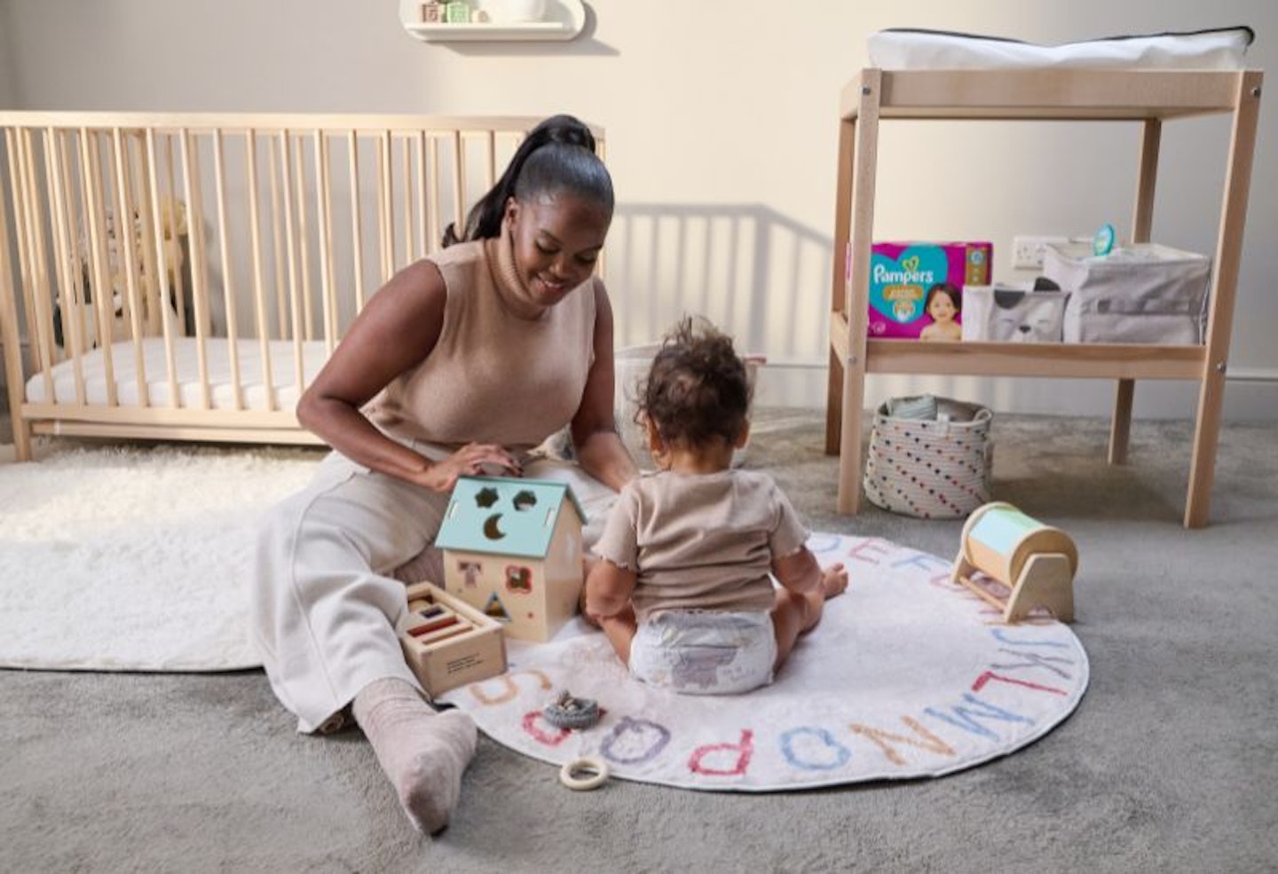 Oti Mabuse sitting in the nursery with her daughter, who is wearing a Pampers nappy