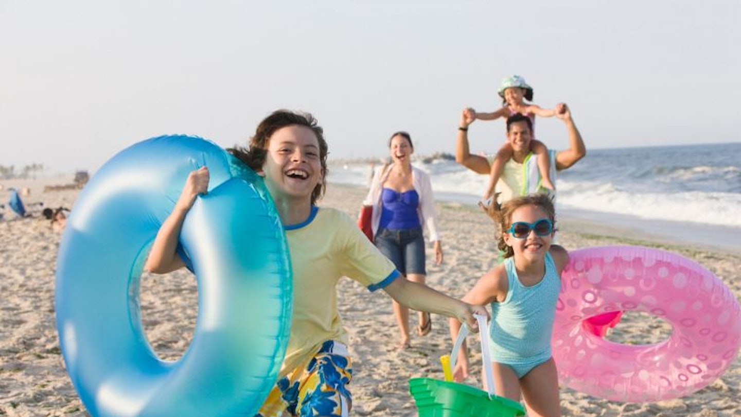 Children with inflatable toys running along a beach