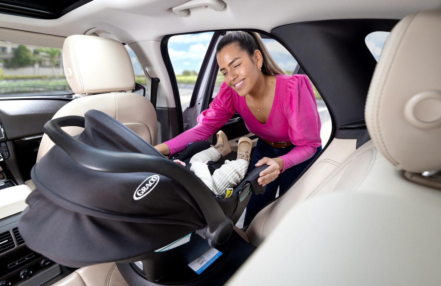 Woman putting child in car seat in car