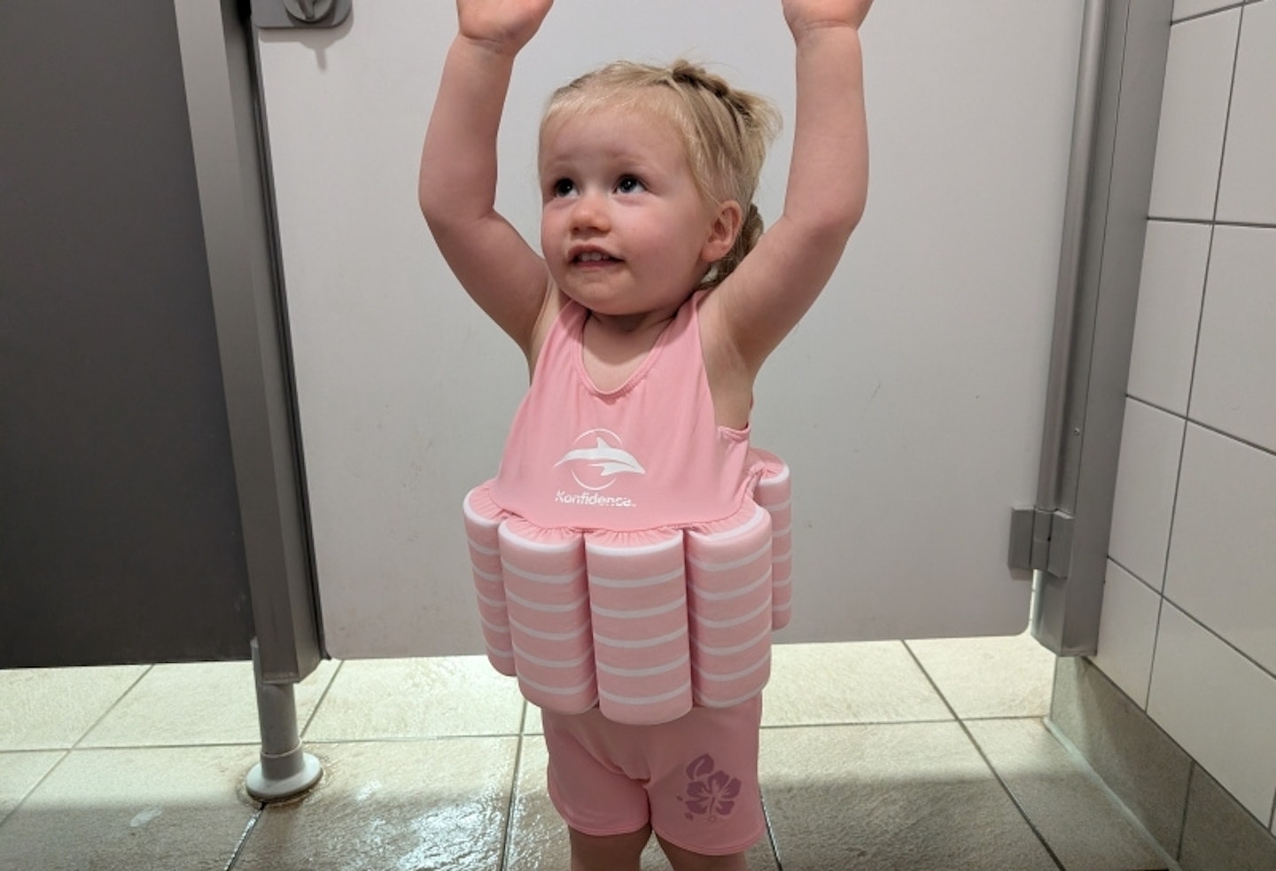 young child wearing the Konfidence Floatsuit, her hands are in the air