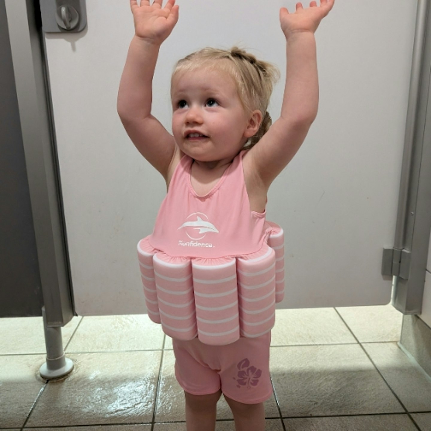 young child wearing the Konfidence Floatsuit, her hands are in the air