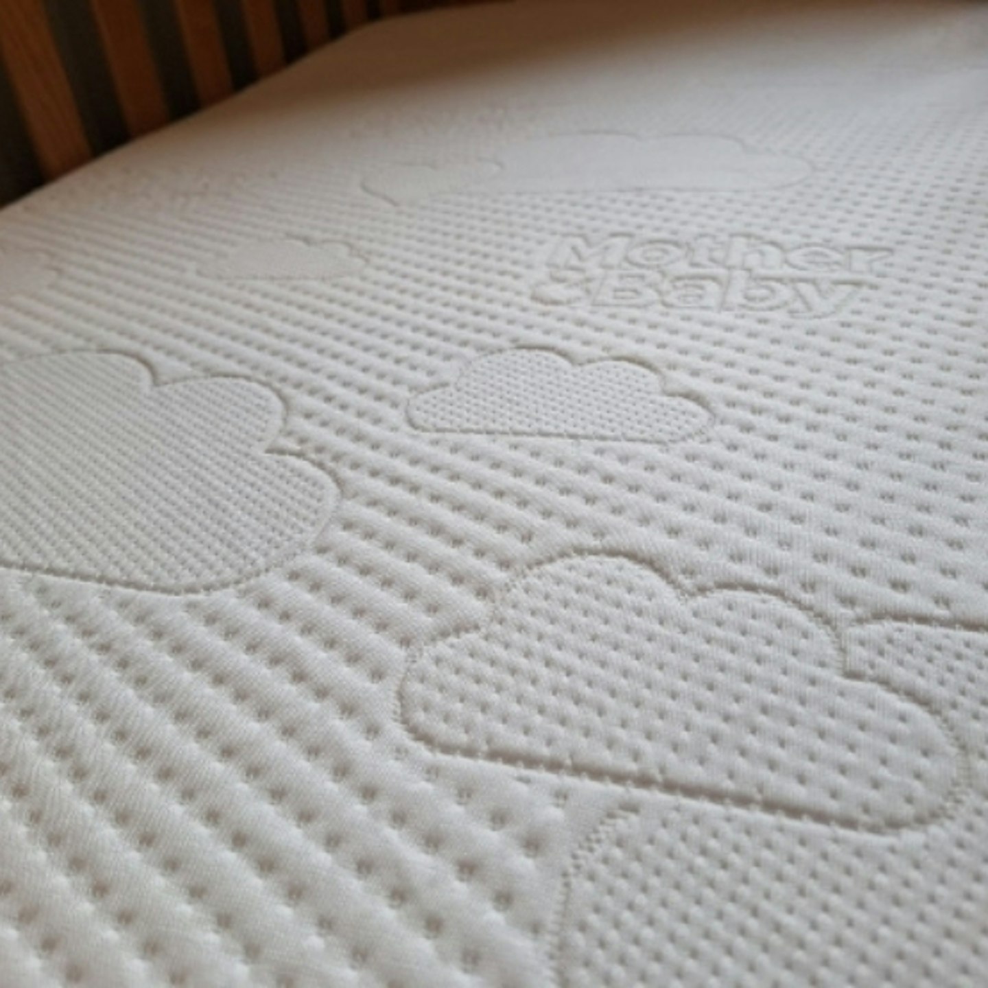 close up photo of the Mother+Baby Pure Gold Anti-Allergy Coir Pocket Cot Bed Mattress, showing the cloud and spot padded pattern on top