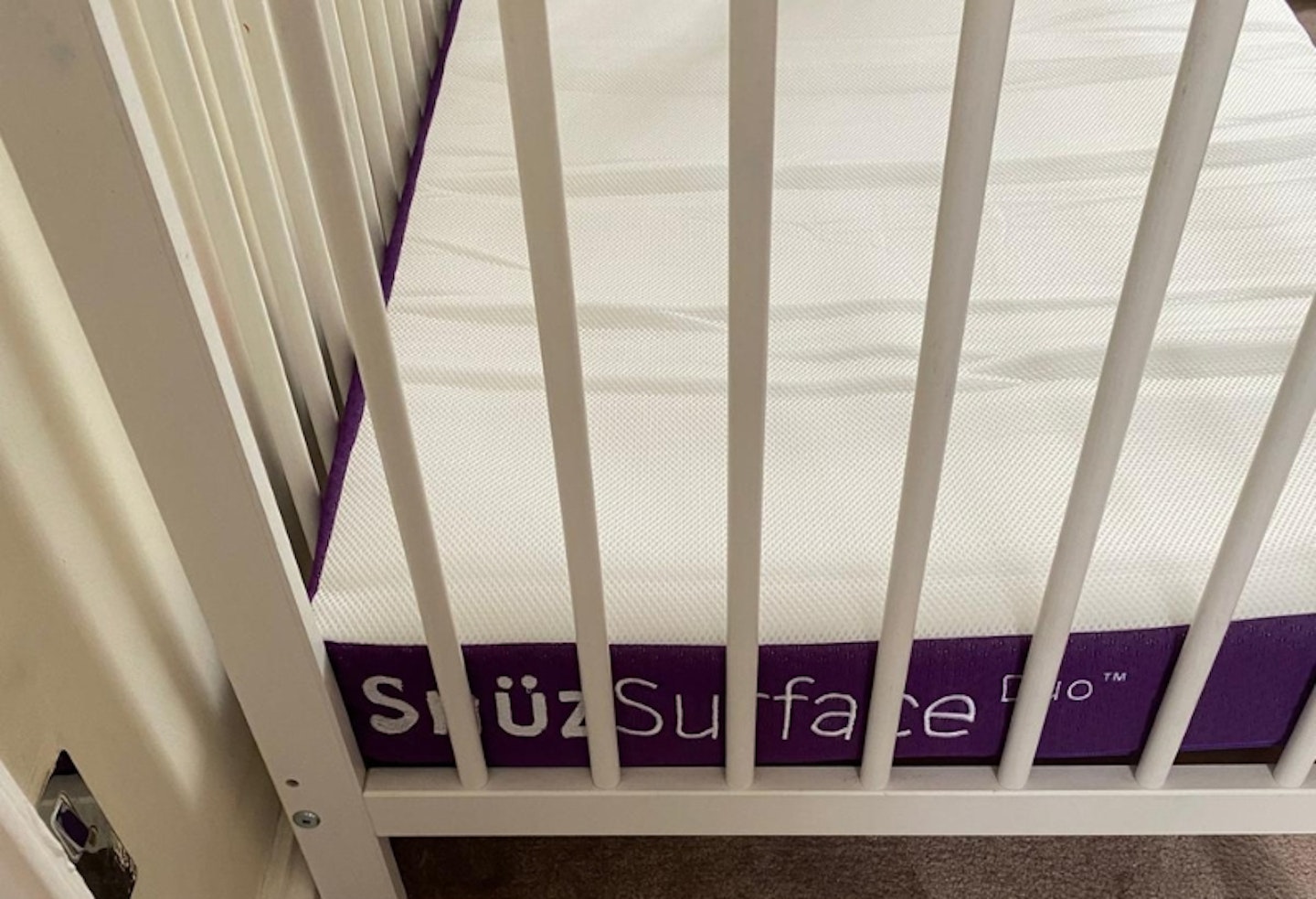 Snuz Surface Pro Duo Cot Mattress in a white cot, showing the purple sides and white top