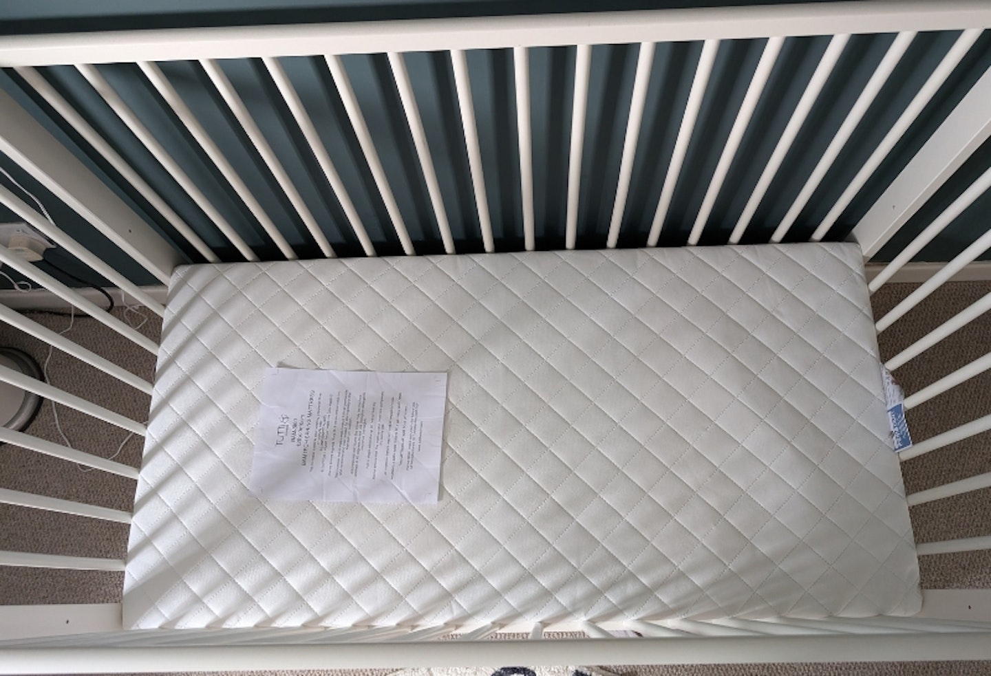 Tutti Bambini Sprung Cot Bed Mattress in a white cot, showing the padded structure of the top of the mattress