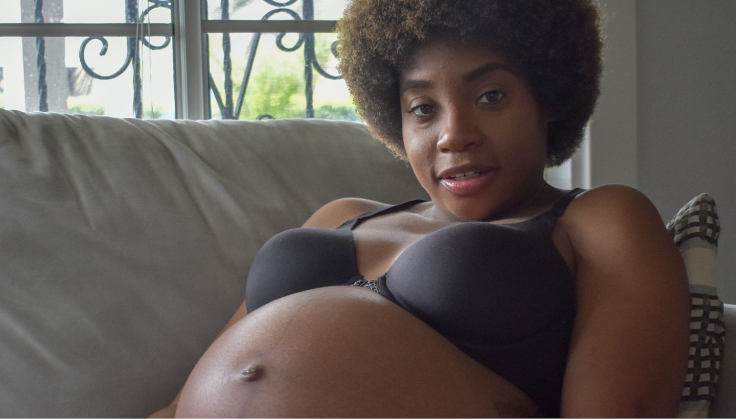 Black pregnant woman wearing a black bra