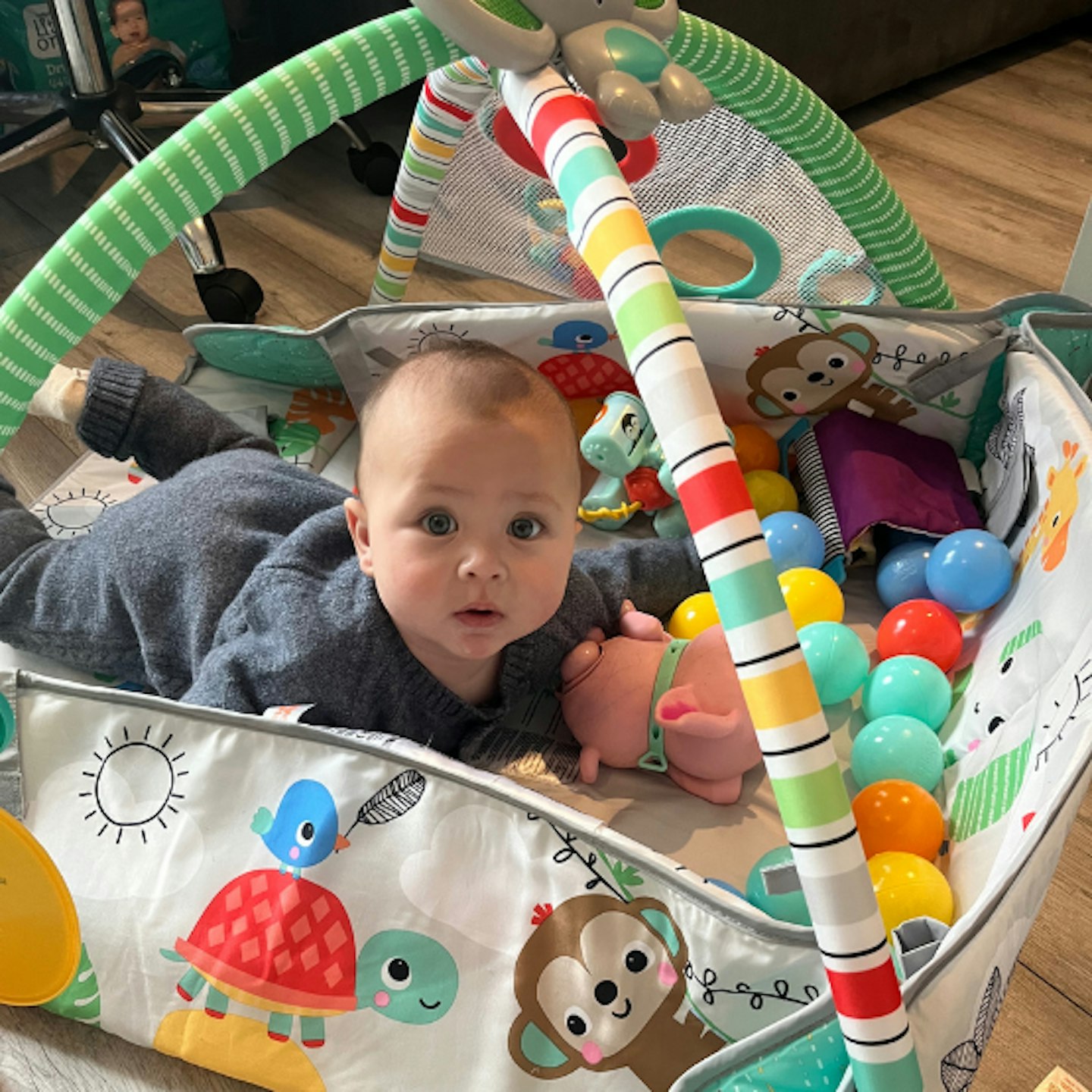 baby lying on their fron in the ball pit of the Bright Starts baby gym