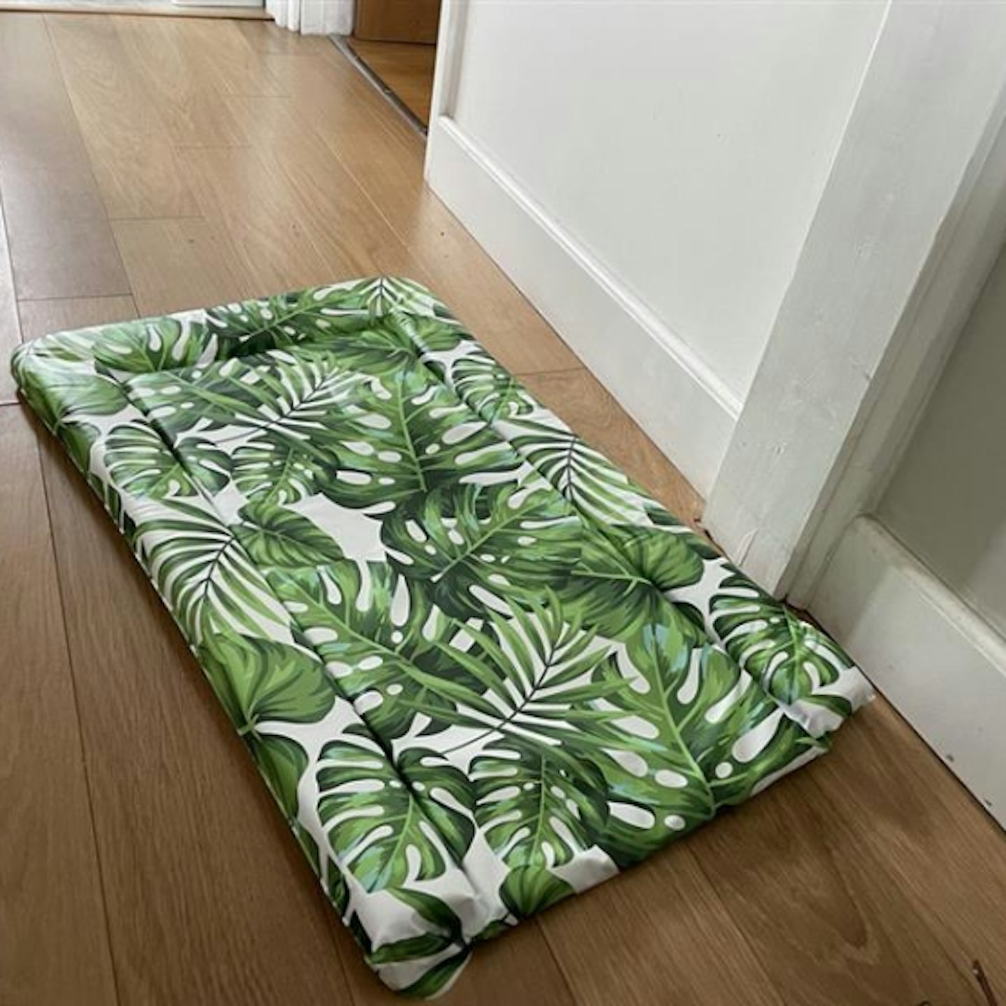 Cuddle Co changing mat with tropical leaf print laying on floor