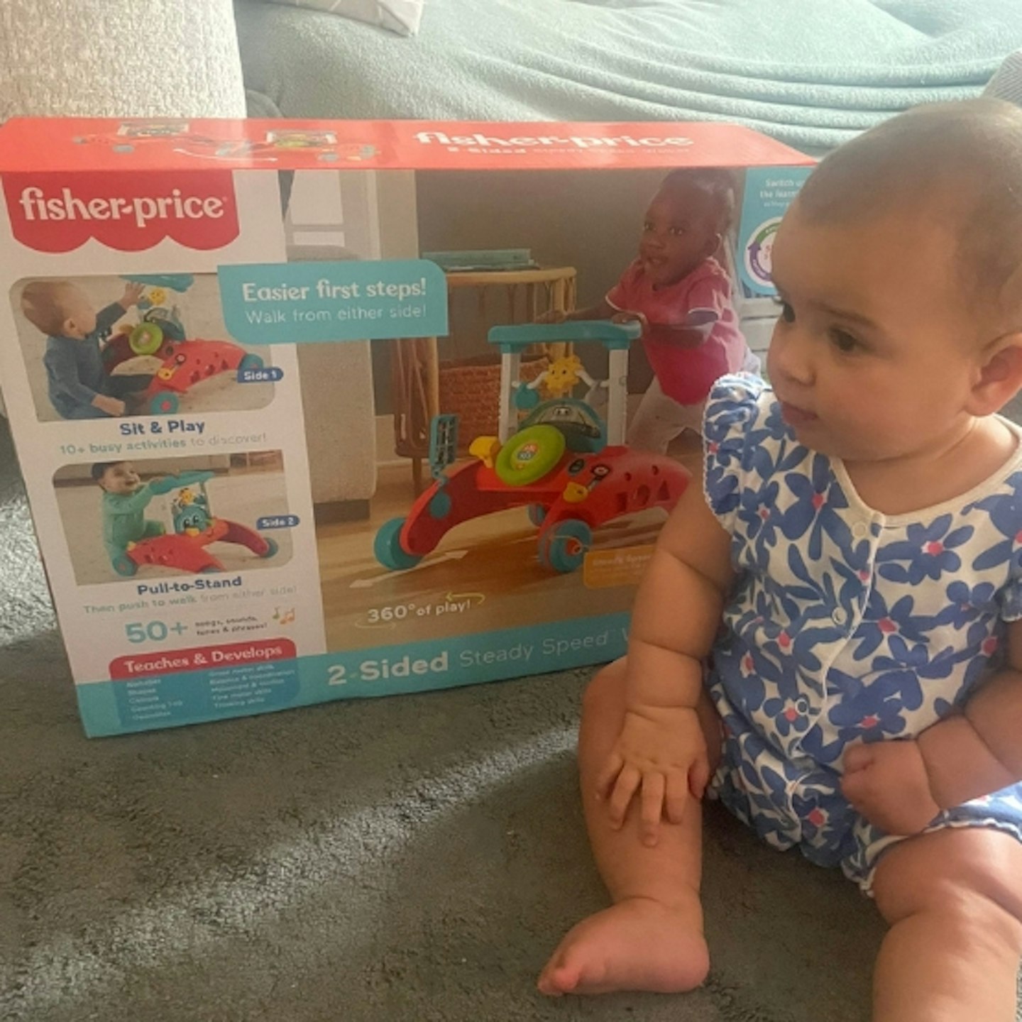 baby sitting next to the Fisher-Price 2-sided steady speed walker in its box