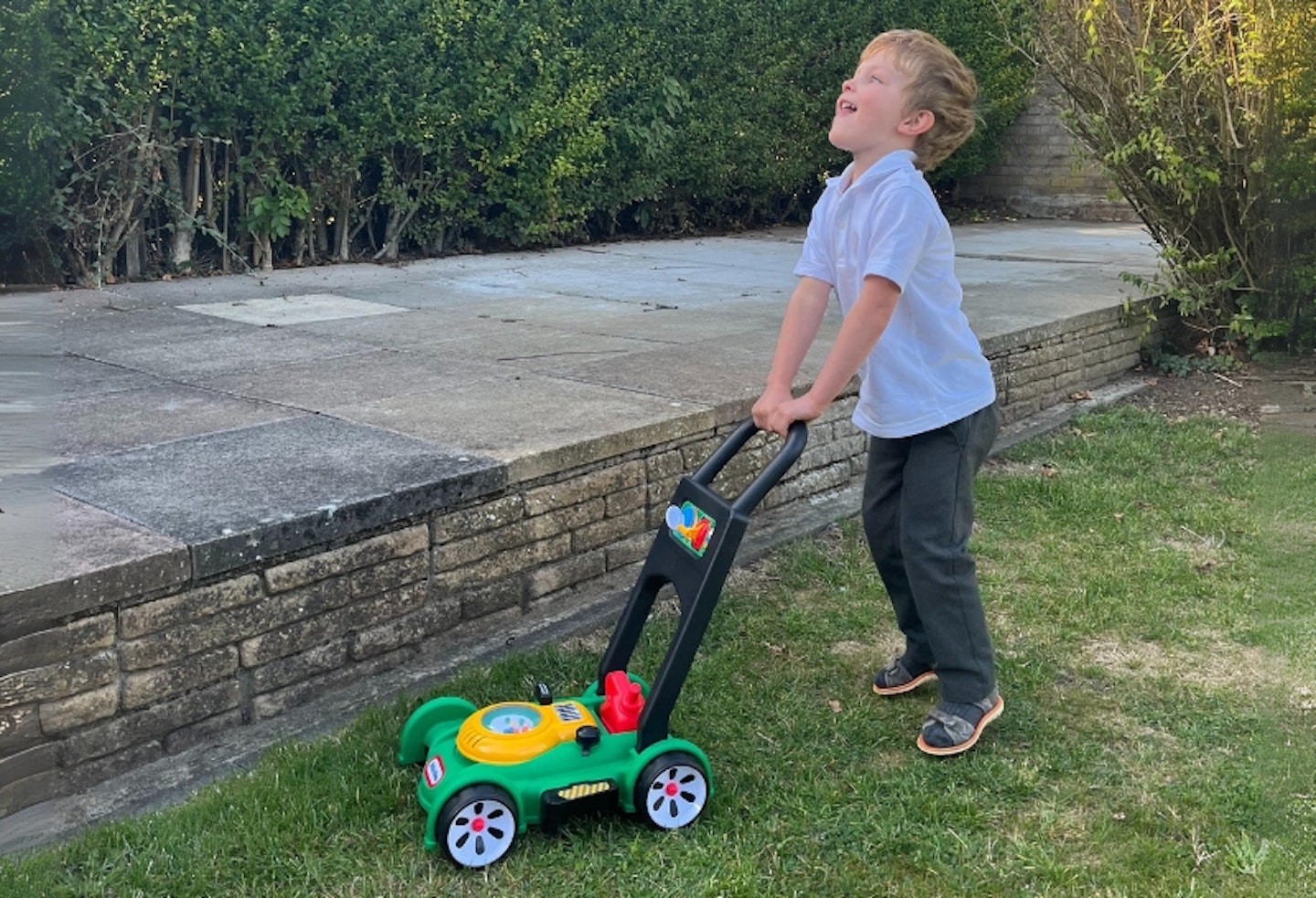 child pushing the Little Tikes Lawnmower outside