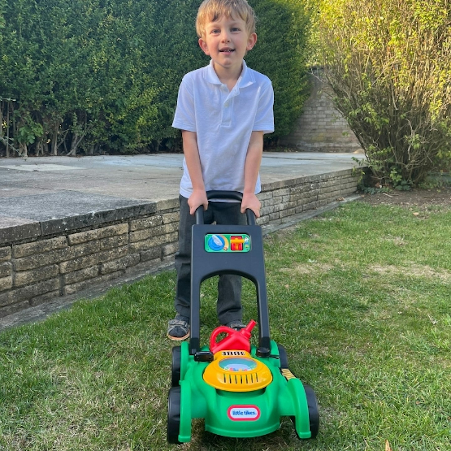 child pushing the Little Tikes Lawnmower outside