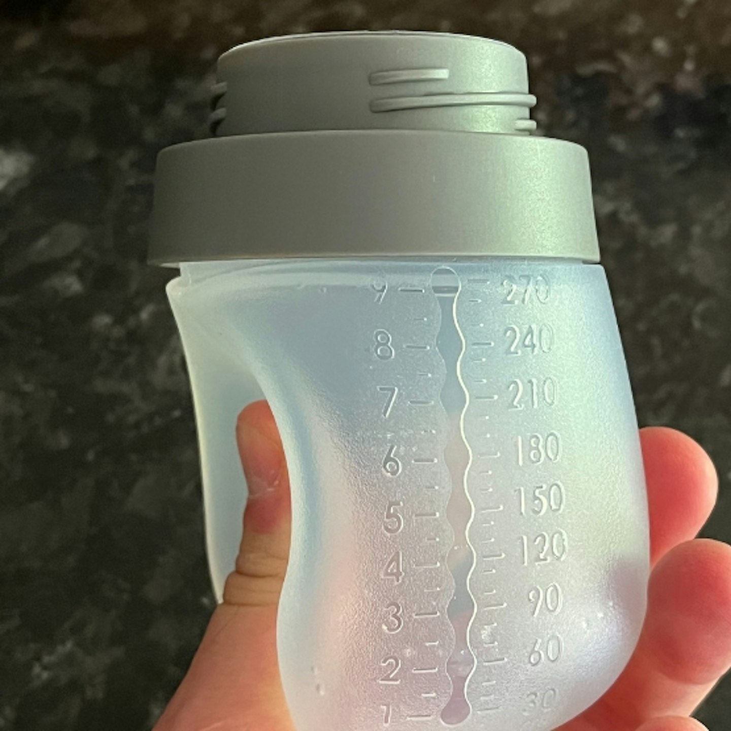 hand squeezing an empty Nanobebe Flexy Silicone Baby Bottle