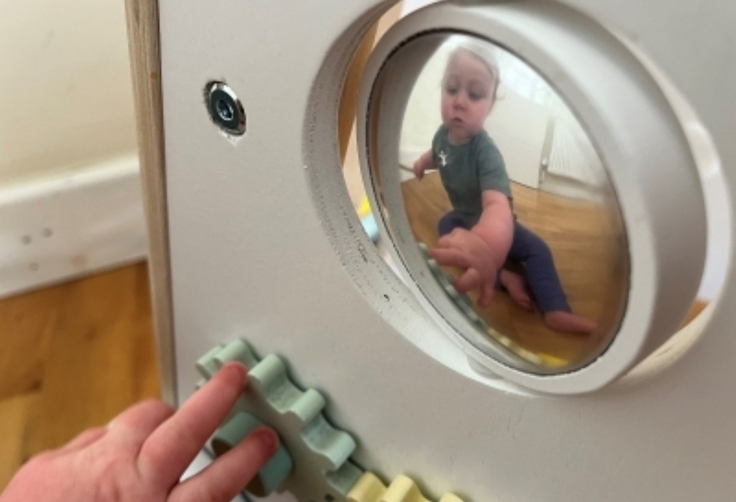 Toddler playing with cogs and rotating mirror on the Sweet Cocoon Wooden Multi-Activity Baby Walker.