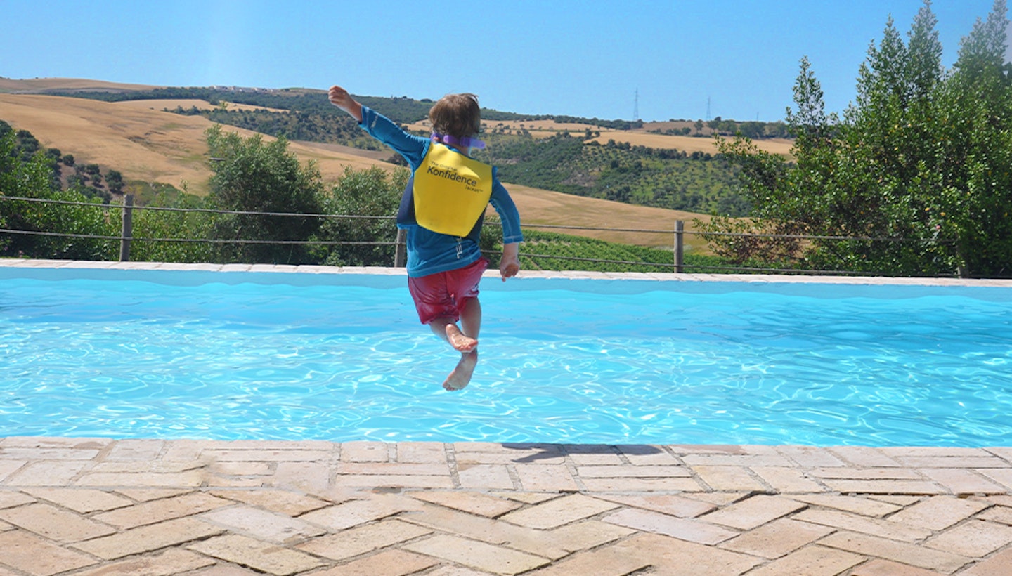 Kid wearing a swim jacket about to jump on the pool