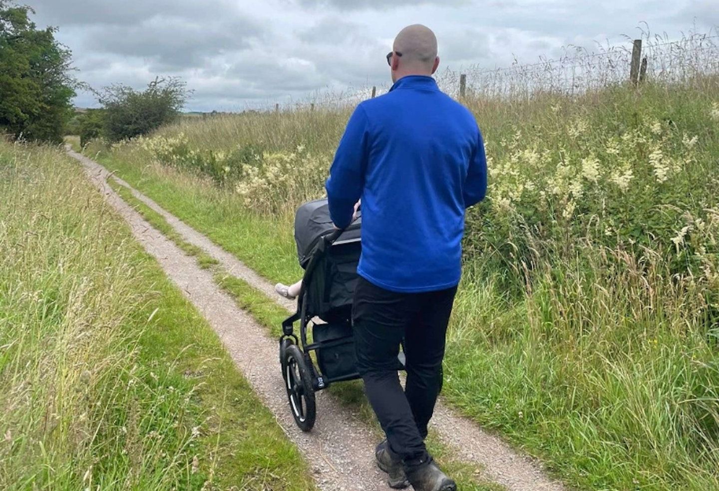 man walking down a path pushing a young child in the Thule urban glide 3