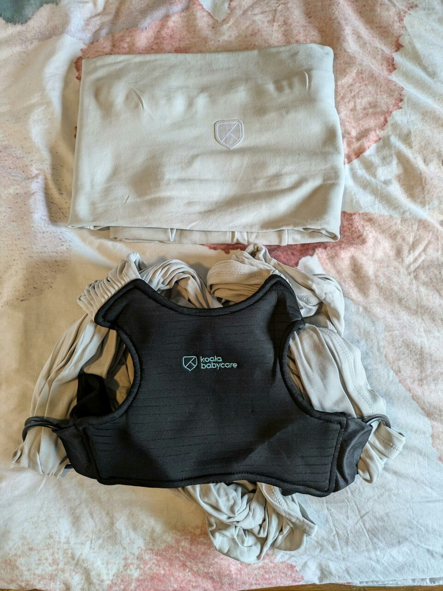 Koala Cuddle Band 2 Baby Sling Carrier laid out on a bed