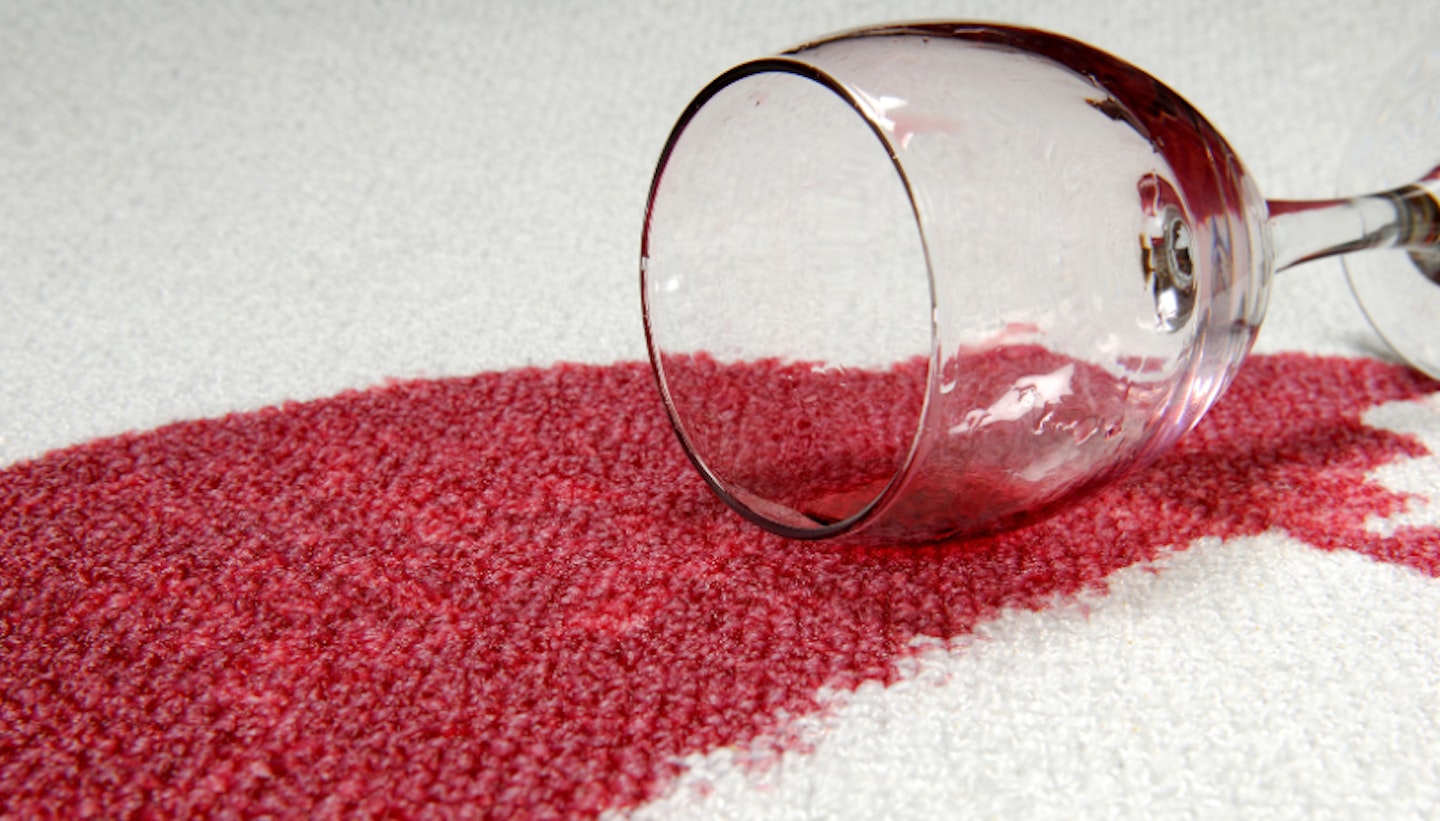 Glass of red wine spilt over carpet