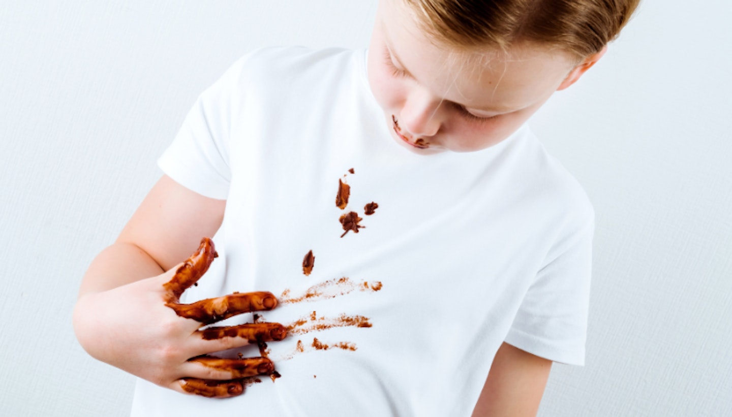 Boy wiping chocolate stains onto his white top