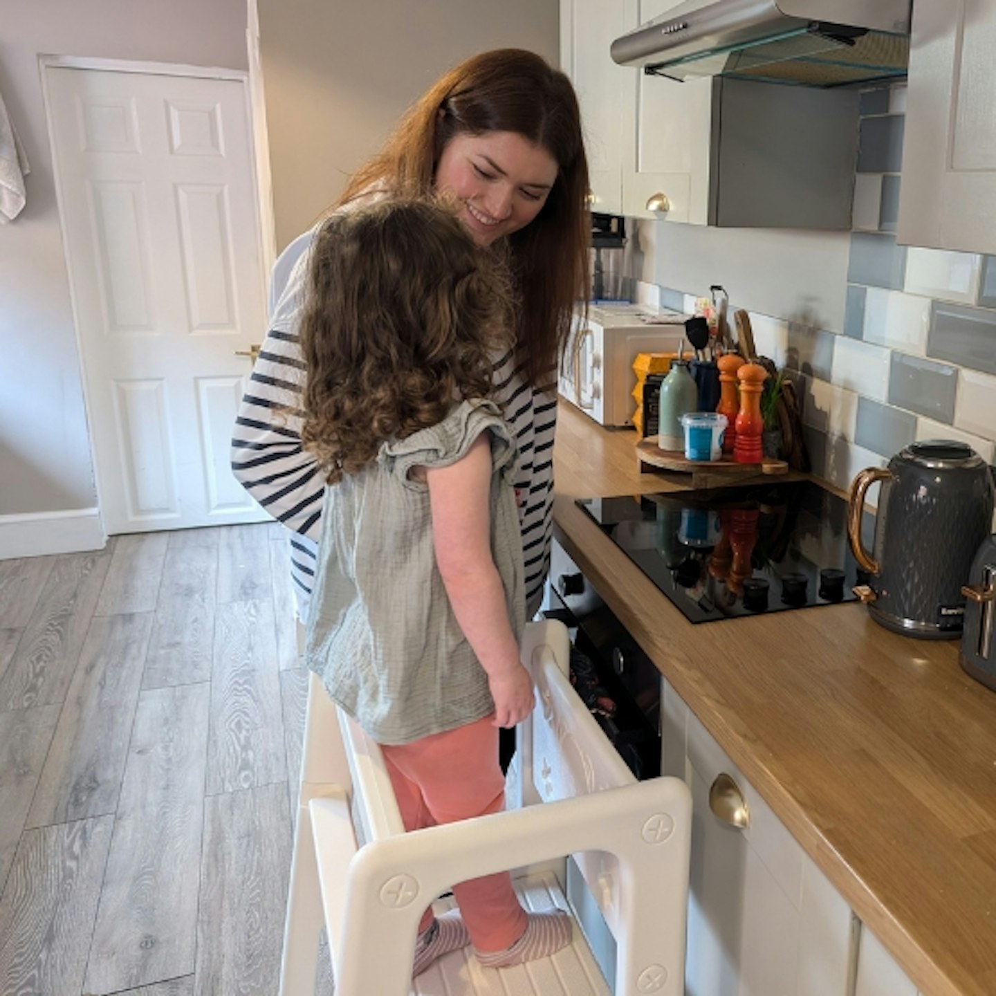 mum stood next to her young child in the HOMCOM Kids Standing Platform in the kitchen