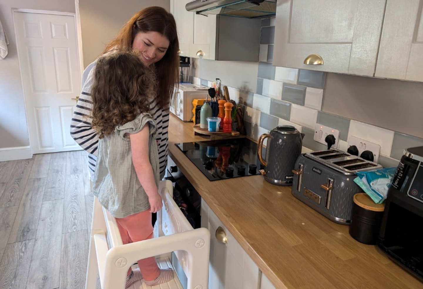 mum stood next to her young child in the HOMCOM Kids Standing Platform in the kitchen