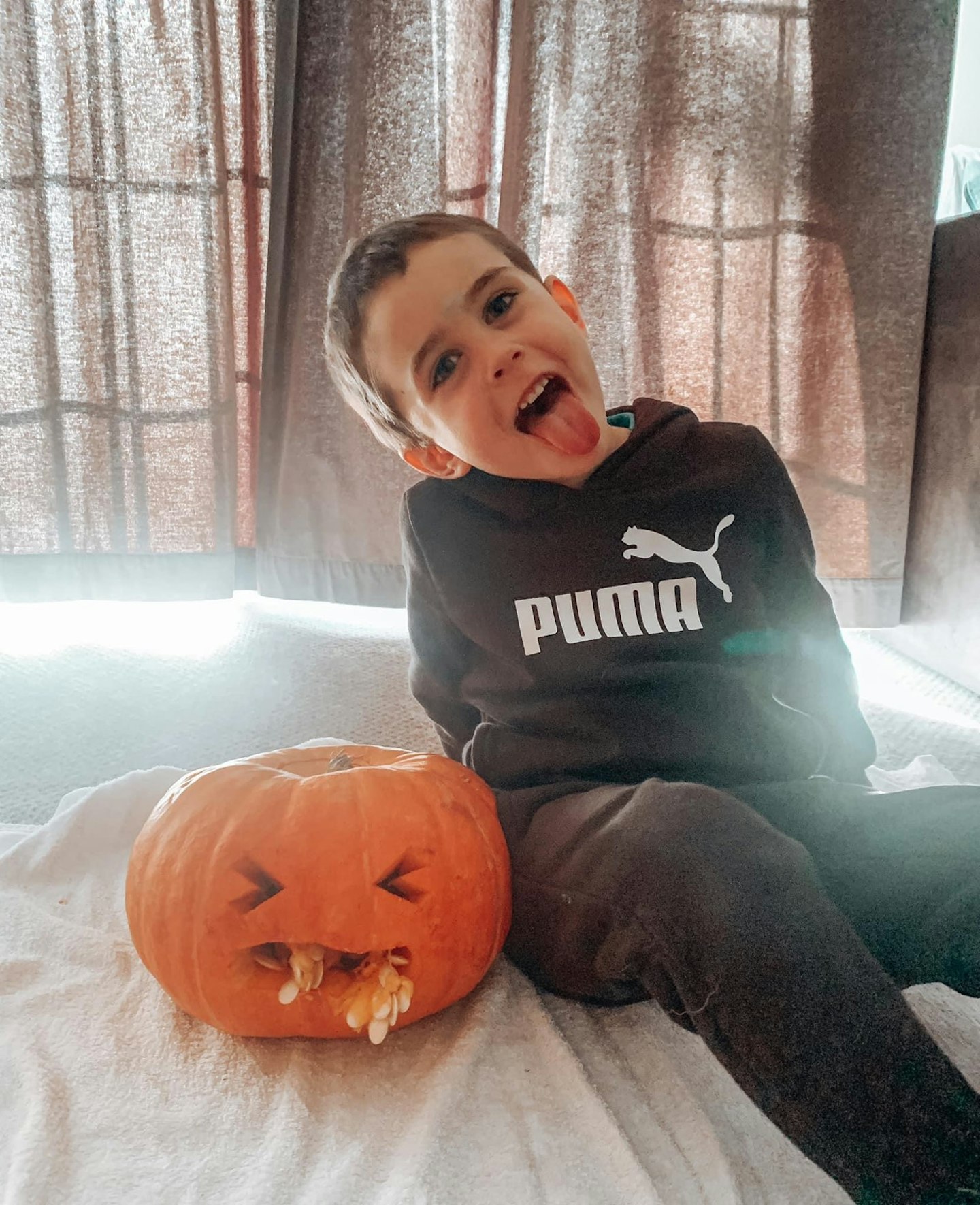 Child sitting next to a carved pumpkin